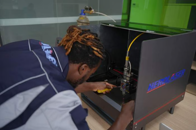 Person working on Herolaser New Laser Cutting machine in a workshop setting.